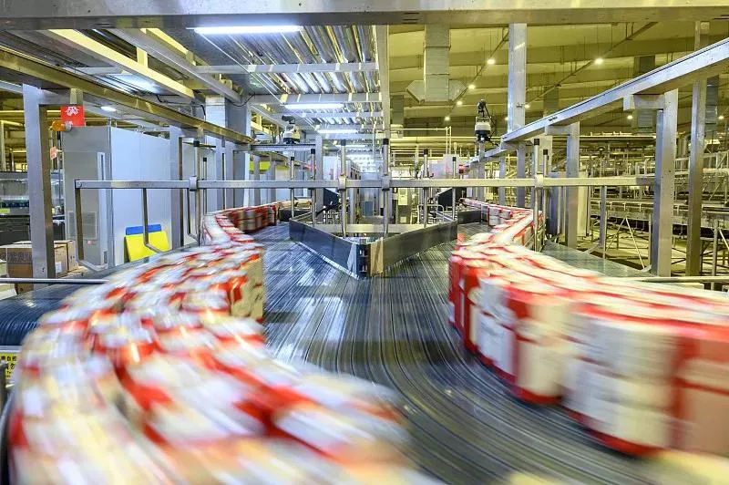 In the scene, a silver 10GigE industrial camera is securely mounted on a precision bracket directly above the production line, its lens focused on industrial parts moving rapidly along the conveyor belt. The prominent "10GigE" label on the side of the camera highlights its cutting-edge high-speed data transmission capabilities. Below the camera, multiple fiber optic cables are neatly arranged, connecting to a high-performance switch equipped with 10G ports, forming a stable and ultra-fast data transmission link. Within the camera's field of view, every detail on the part's surface is captured with exceptional clarity. With a shooting speed of up to hundreds of frames per second and the 10GigE protocol, high-definition image data is transmitted in real-time to the backend inspection system at near-10Gbps bandwidth, enabling millisecond-level defect detection and analysis. This setup provides a robust foundation for automated industrial quality inspection.